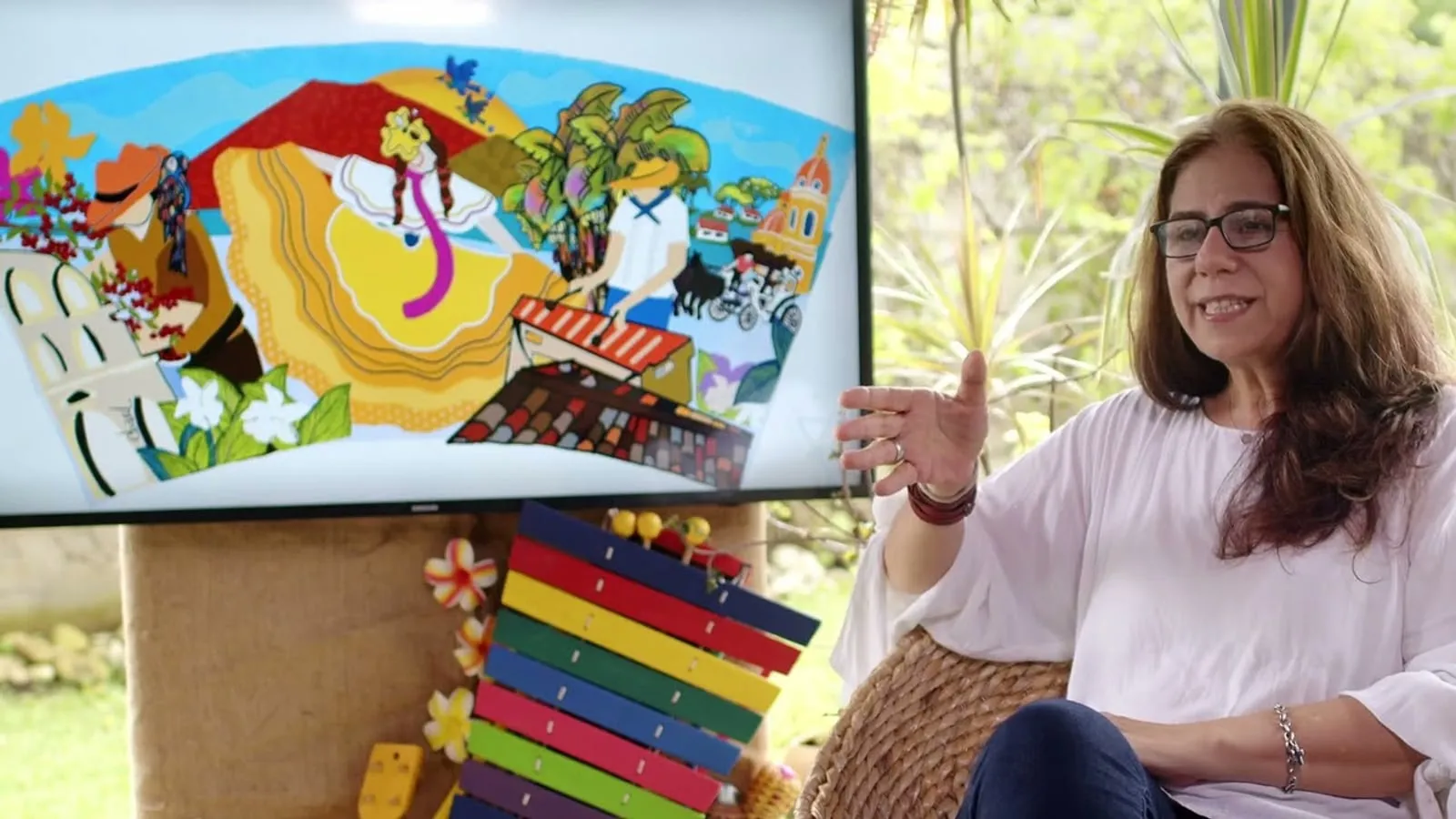 Elsa Basil speaking on camera beside a screen showing her colorful Café PRESTO mug illustration