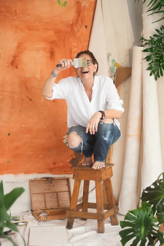 Elsa Basil laughing with a paintbrush held over her eyes